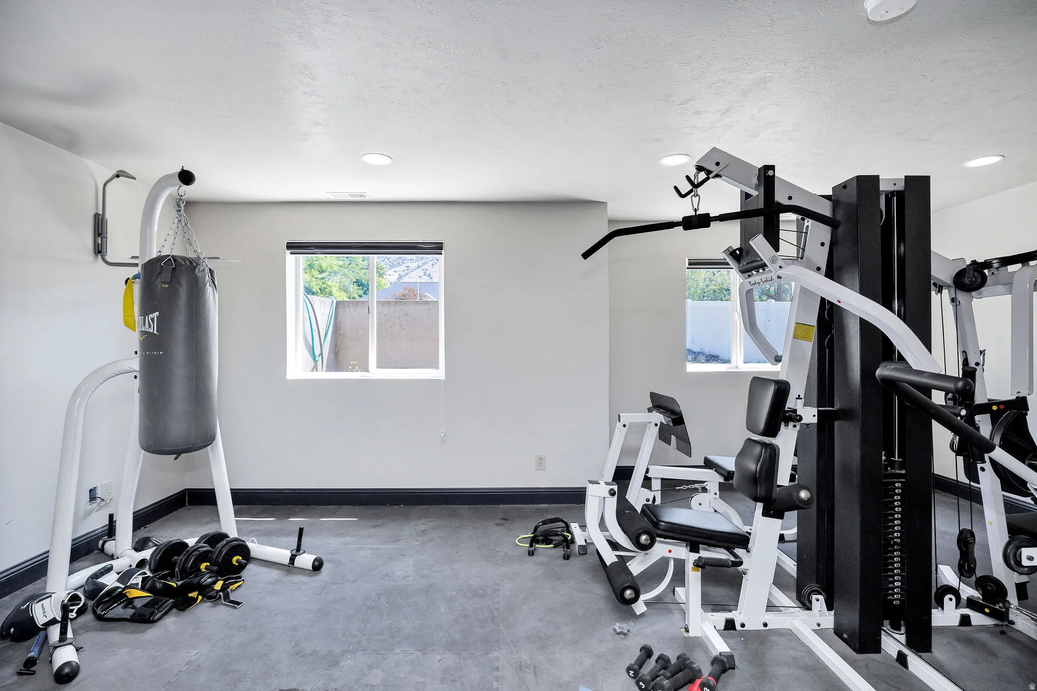 Dedicated fitness space featuring recessed lighting, two windows, and dark-finish baseboards
