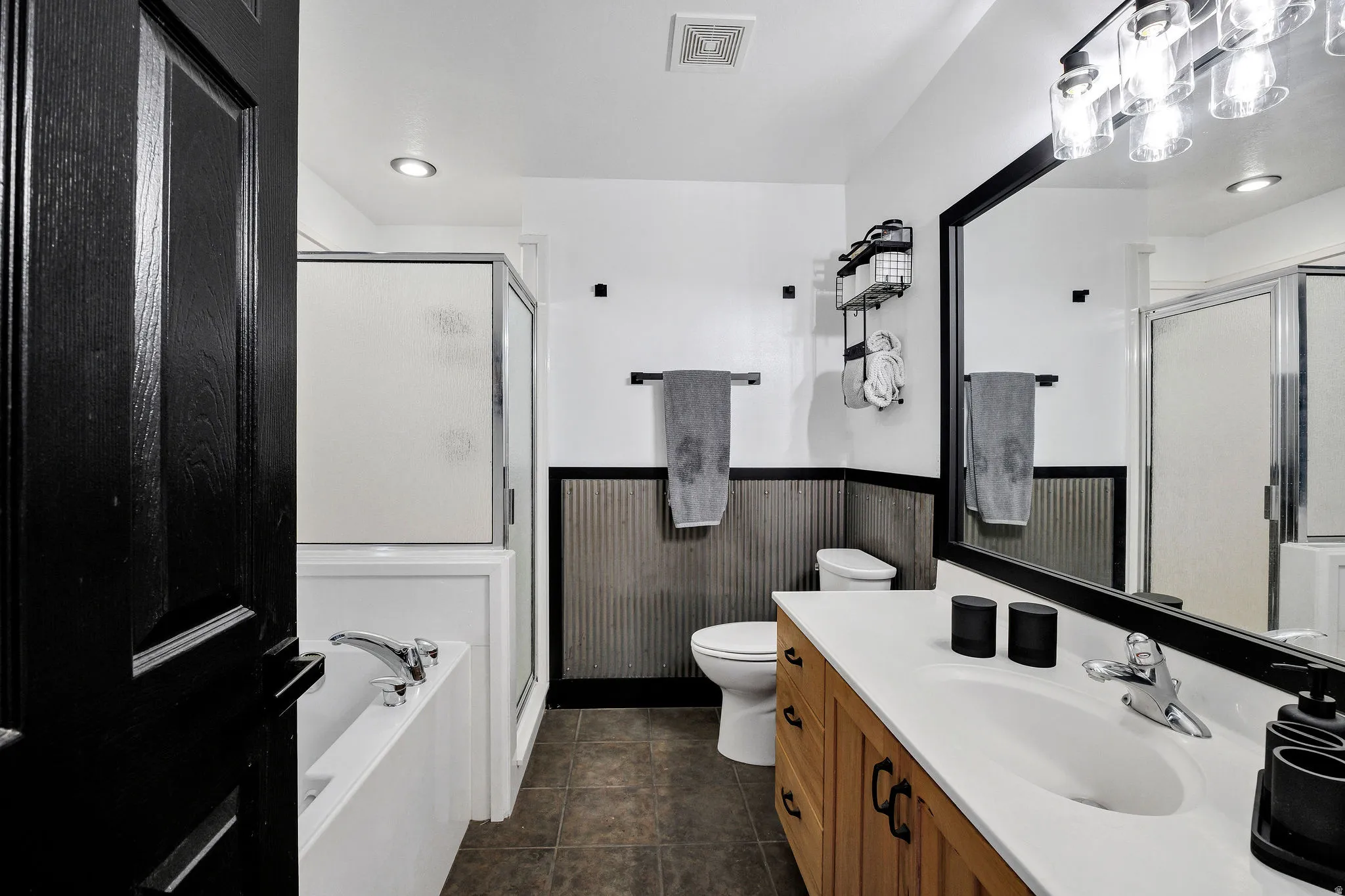 Full bathroom featuring a single vanity with wood-finish cabinetry, a white countertop, and an undermount sink