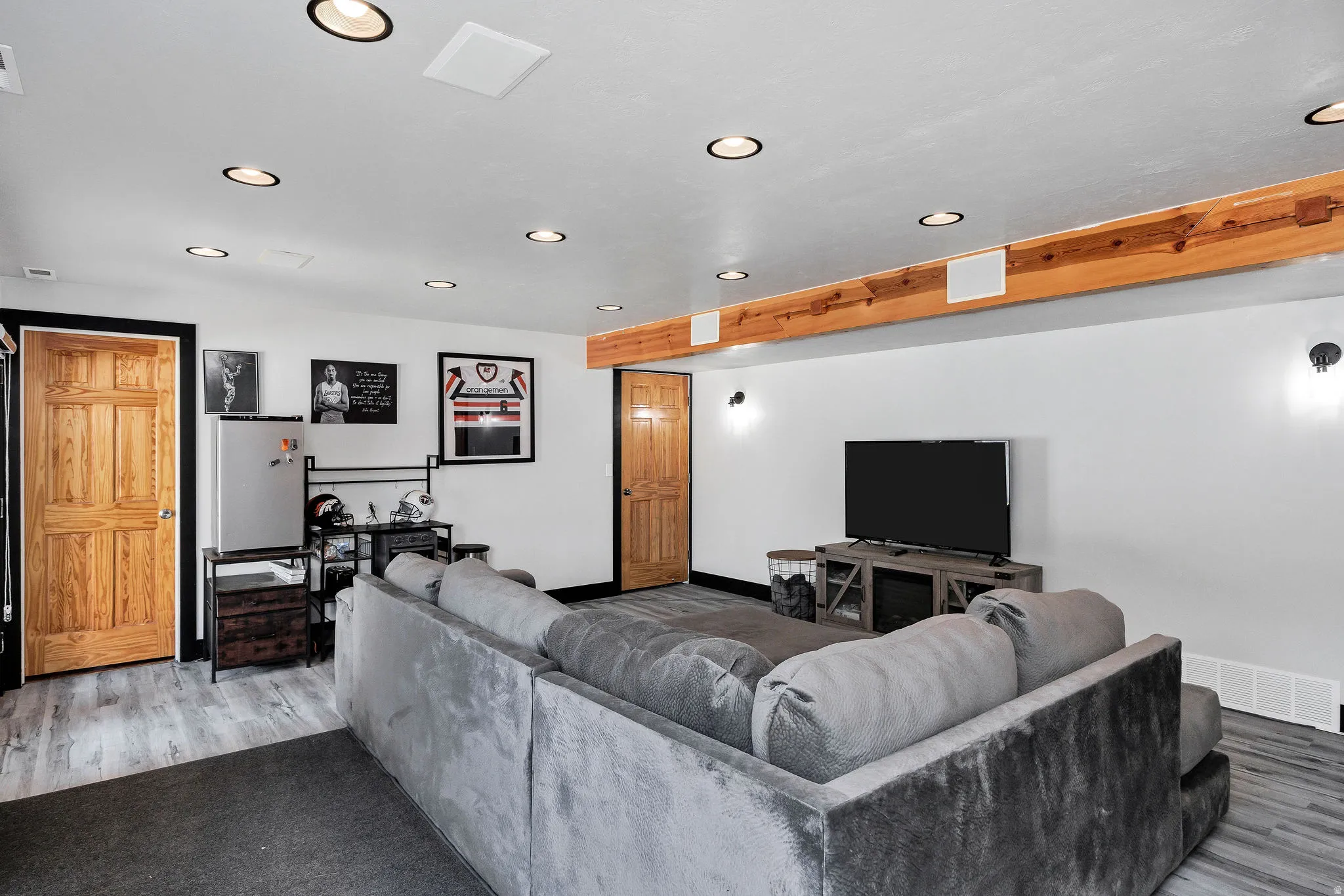 Recreational space featuring recessed lighting, exposed wood beams, wood-finish flooring, two wood panel doors, and integrated ceiling speakers
