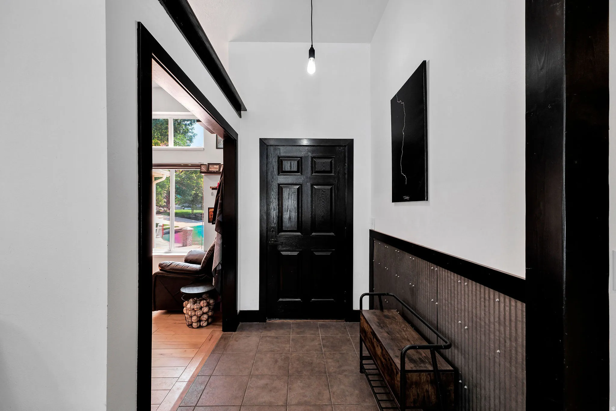Entryway featuring contrasting dark trim and a six-panel door, corrugated metal wainscoting, and tile flooring