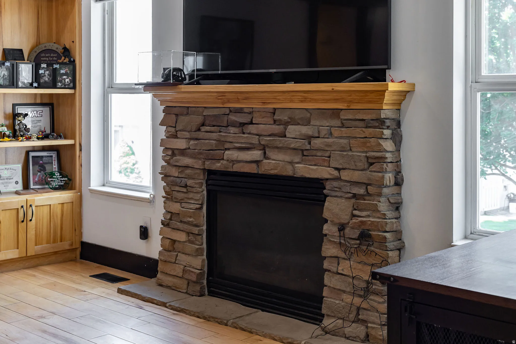 Stacked stone fireplace with a wood-finish mantel and hearth