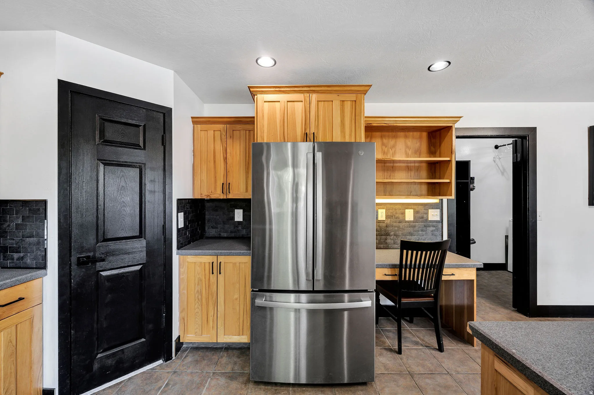 Stainless steel refrigerator integrated into wood cabinetry with under-cabinet lighting