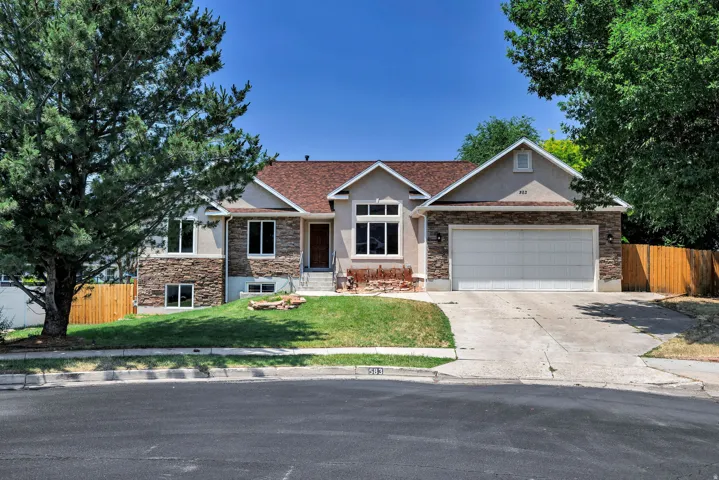 Split-level residence featuring a stucco and stone veneer facade, a two-car garage, and a concrete driveway