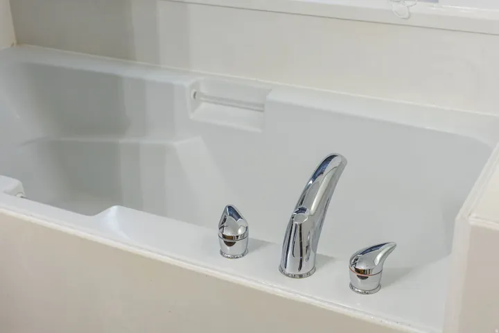 Built-in white soaking tub featuring chrome fixtures and a surrounding white tile surface