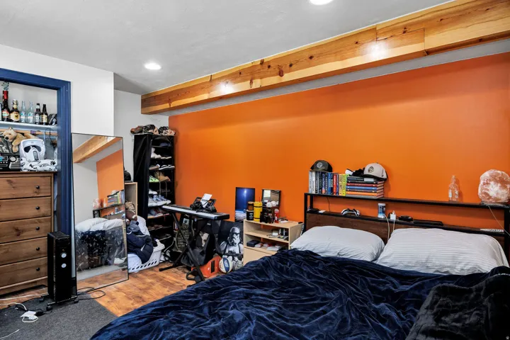 Bedroom with wood-finish flooring, recessed lighting, and an exposed wood beam