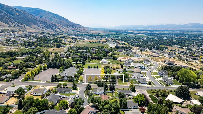 Expansive aerial showcasing a residential neighborhood with surrounding mountains and green spaces