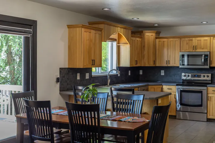 Kitchen featuring wood-finish cabinetry, stainless steel appliances, dark subway tile backsplash, and recessed lighting
