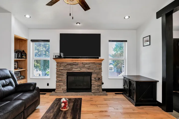 Living space featuring a stone-clad fireplace with a wood mantel, overhead recessed lighting, and wood-finish flooring
