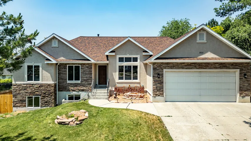 Contemporary residence featuring a brown shingle roof, light stucco, and stacked stone facade
