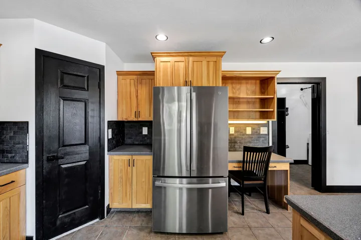 Stainless steel refrigerator integrated into wood cabinetry with under-cabinet lighting