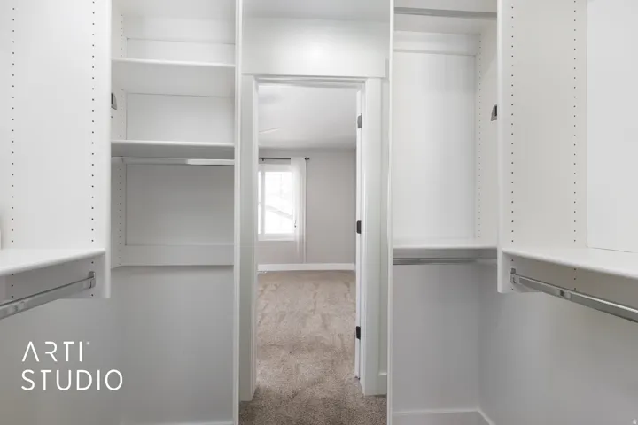 Master bedroom white custom closet organization system featuring adjustable shelving and chrome hanging rods