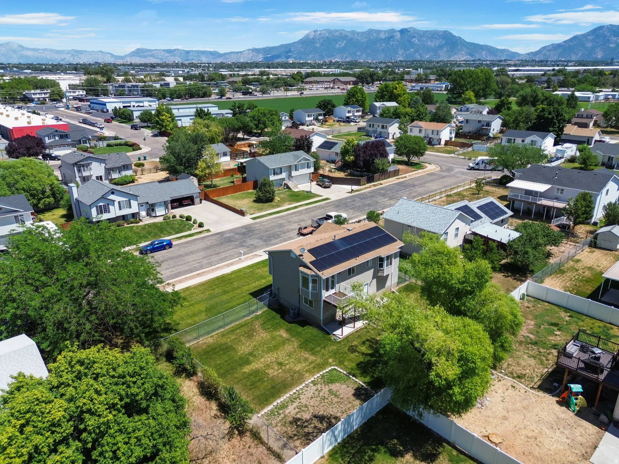 Two-story residence featuring a neutral exterior, a rear deck, and a fenced backyard with a lawn area