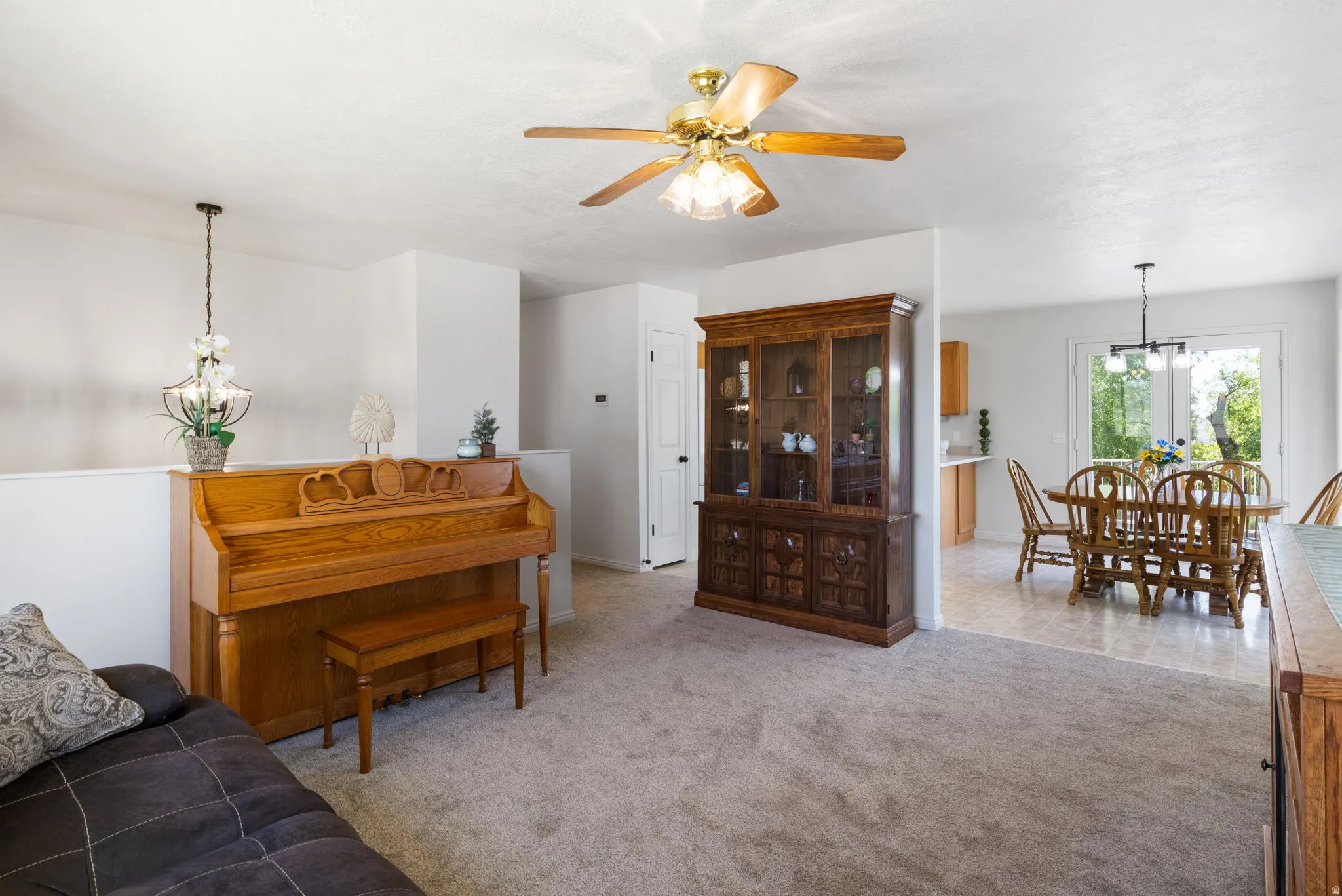 Carpeted living area with a ceiling fan, a partial wall, and a staircase