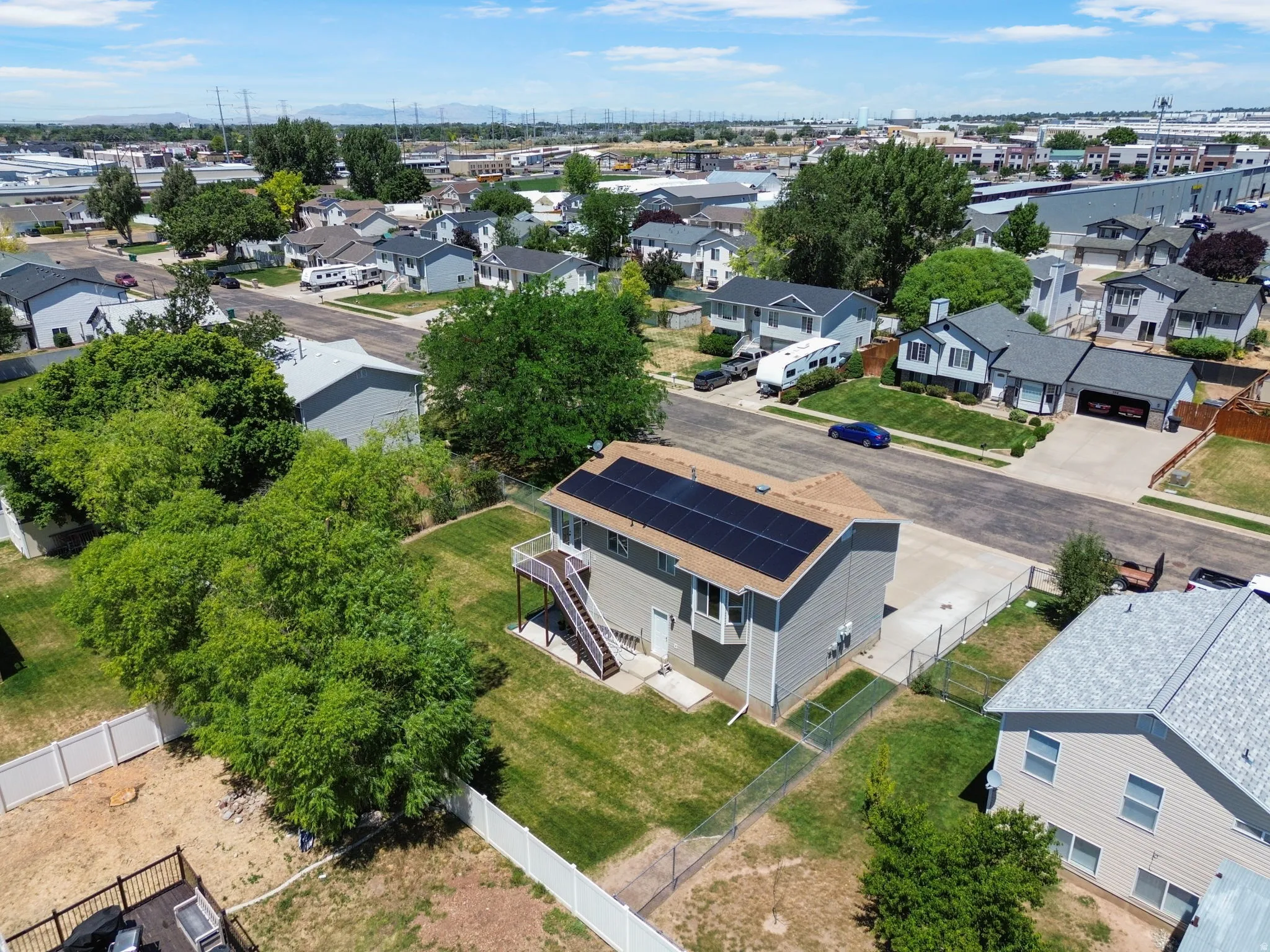 Two-story residence featuring a neutral exterior, solar panels, and a rear deck with stairs descending to a green lawn