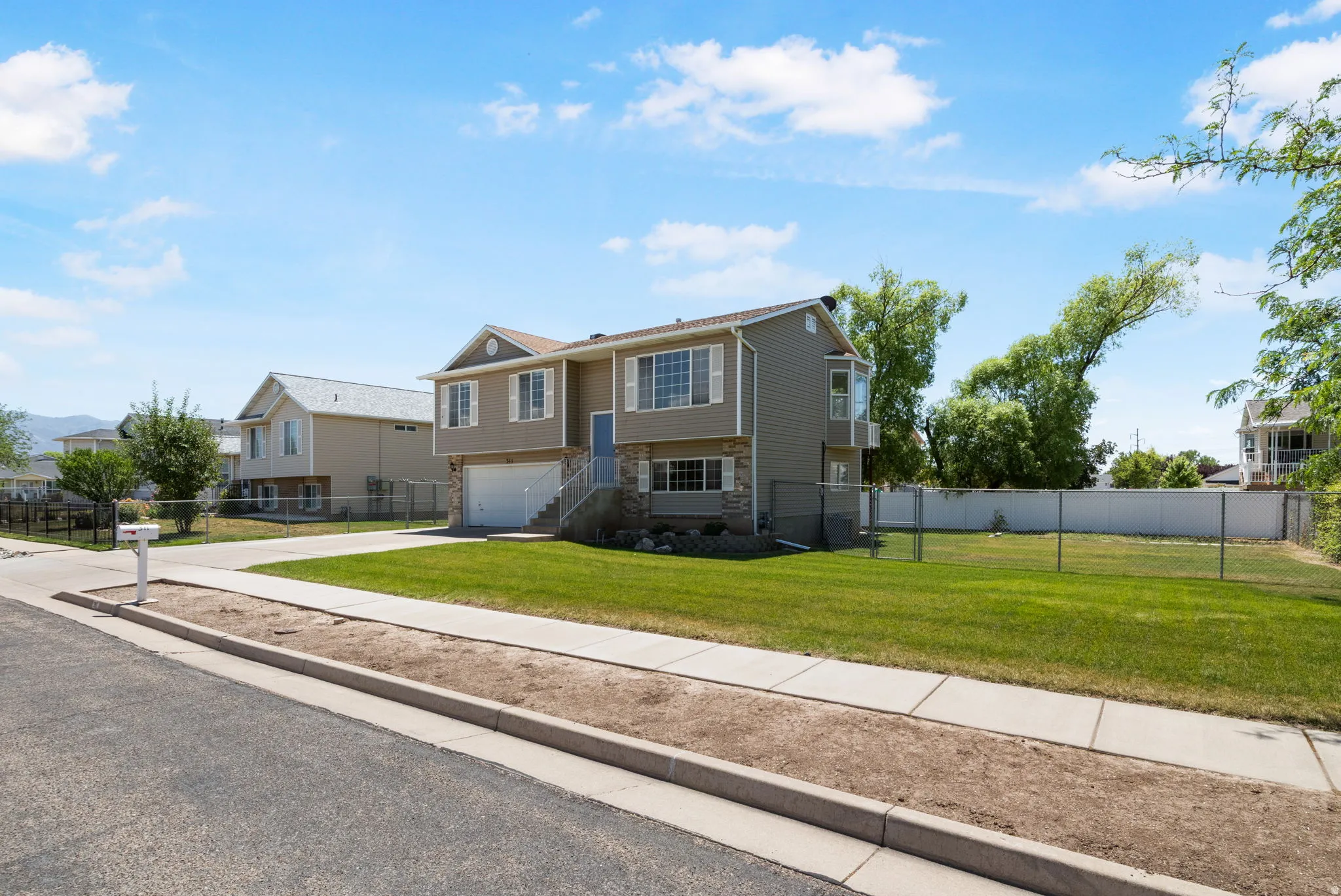 Two-story residence featuring a two-car garage, stone facade accents, bay windows, and a generously sized grassy yard