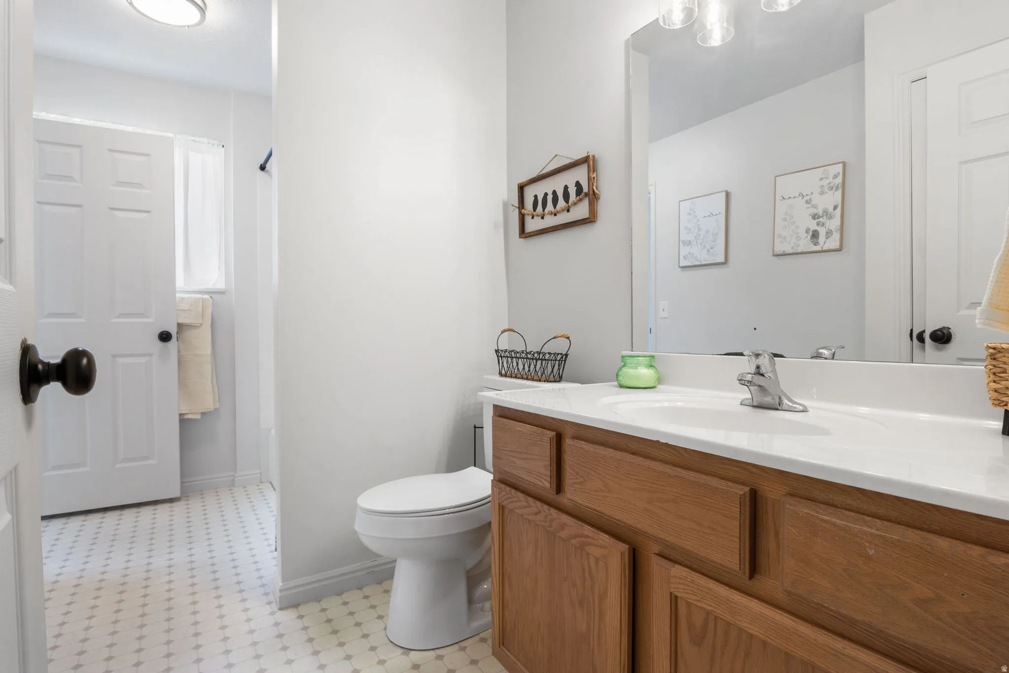 Bathroom featuring a wood-finish vanity with an integrated sink and a large wall-mounted mirror