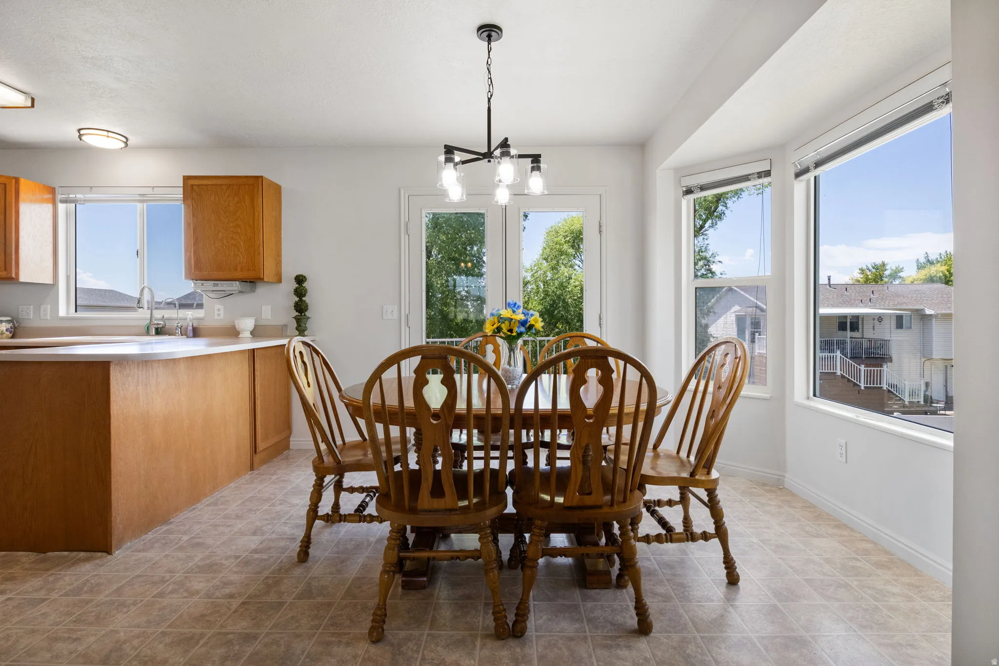 Dining area with patterned tile flooring, a contemporary chandelier, and a bay window
