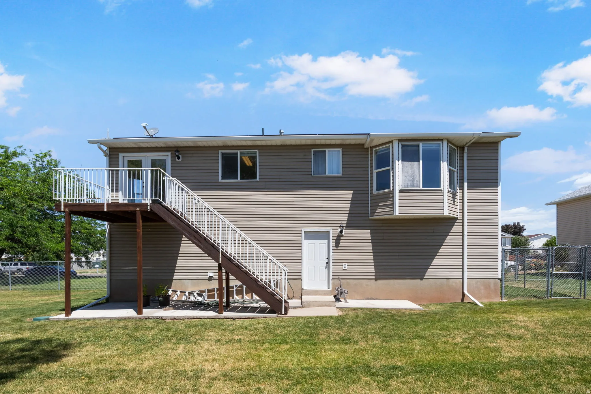 Exterior featuring tan siding, a bay window, and a wood deck with white railings