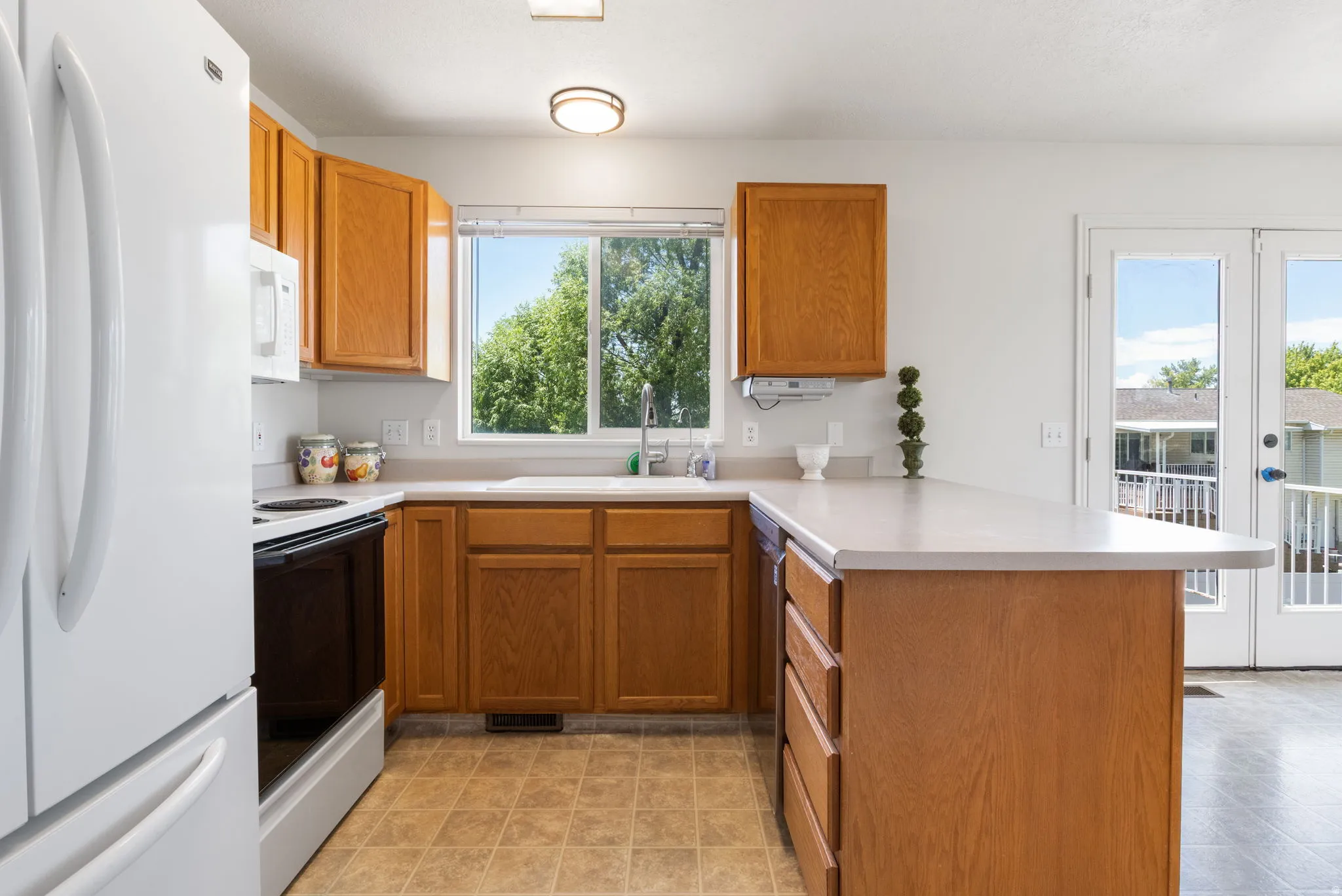Kitchen featuring warm wood cabinetry, light countertops, a window overlooking greenery, and a built-in island