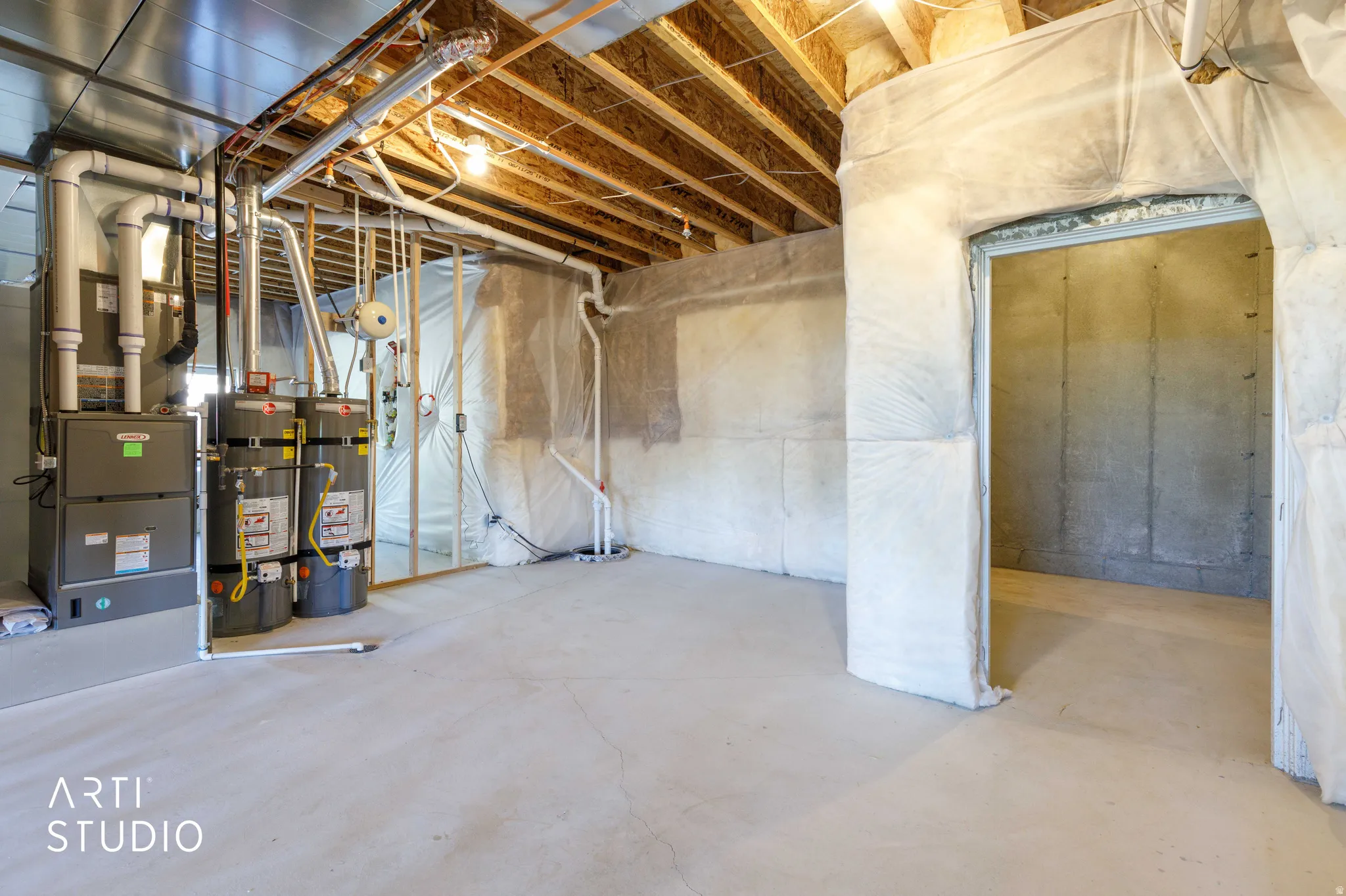 Unfinished basement space with exposed wooden ceiling joists and concrete flooring