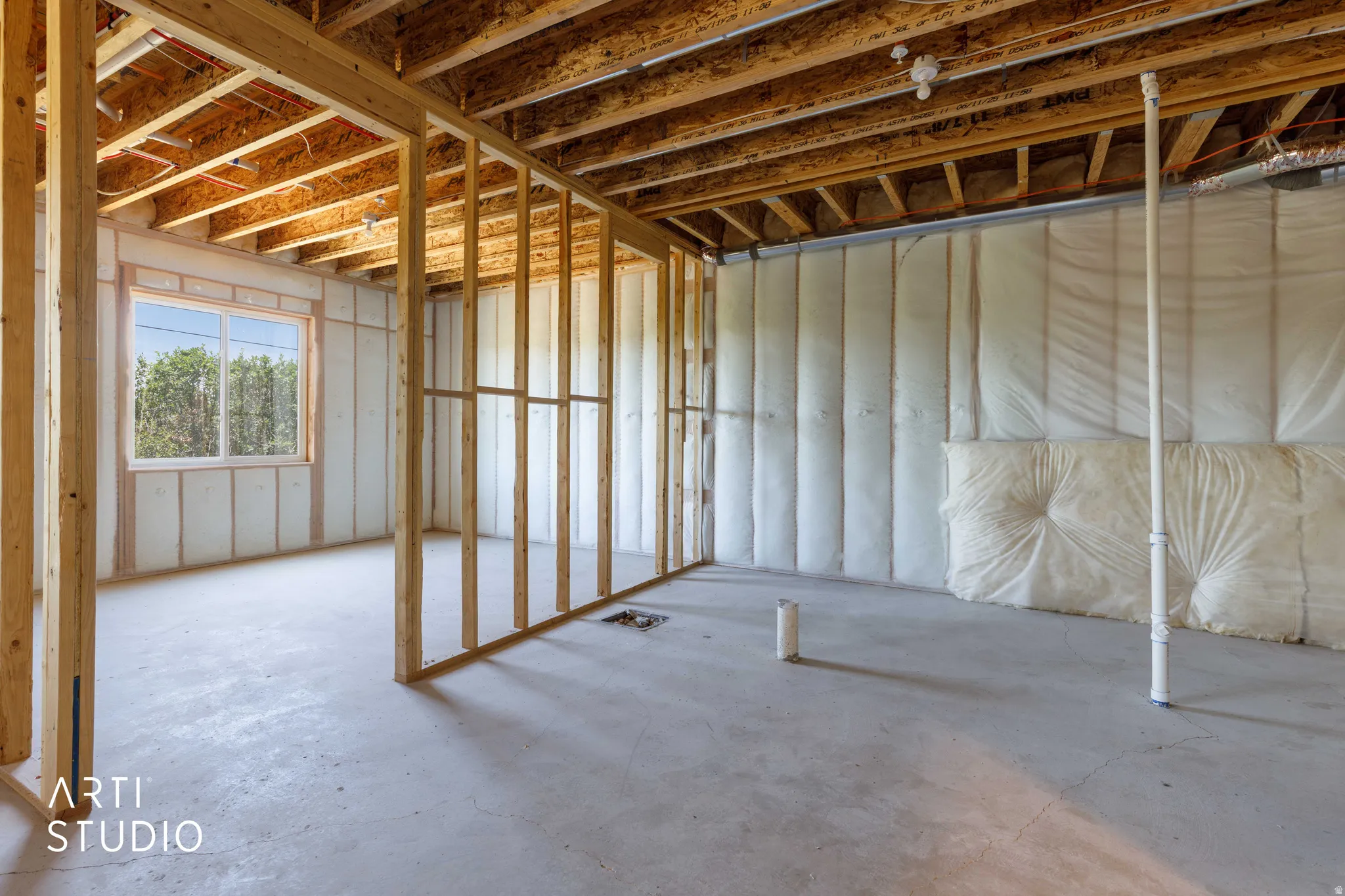 Unfinished interior space featuring exposed wood framing, concrete flooring, and insulated walls