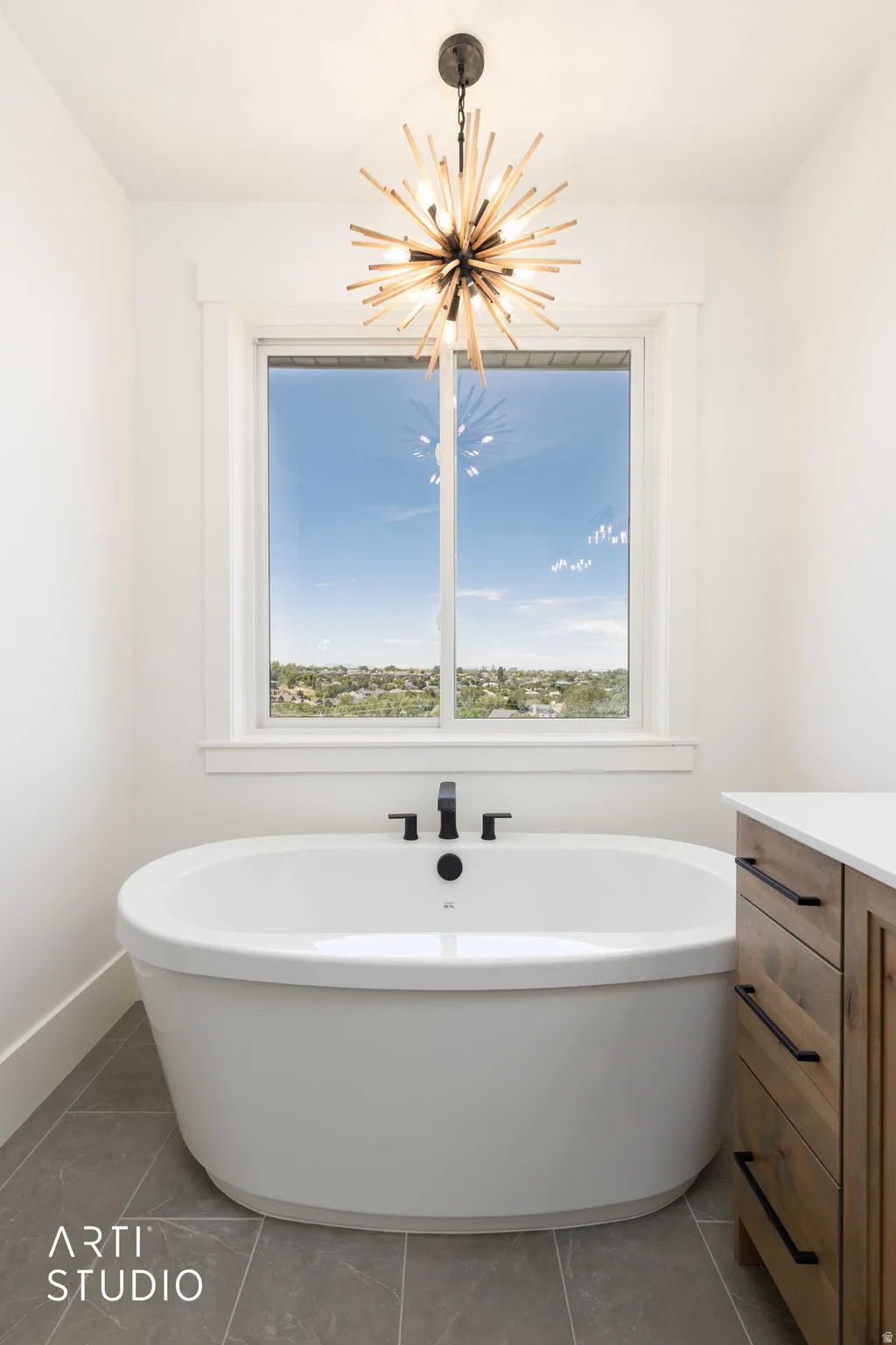 Freestanding oval soaking tub with matte black fixtures, set against a window with a broad sill
