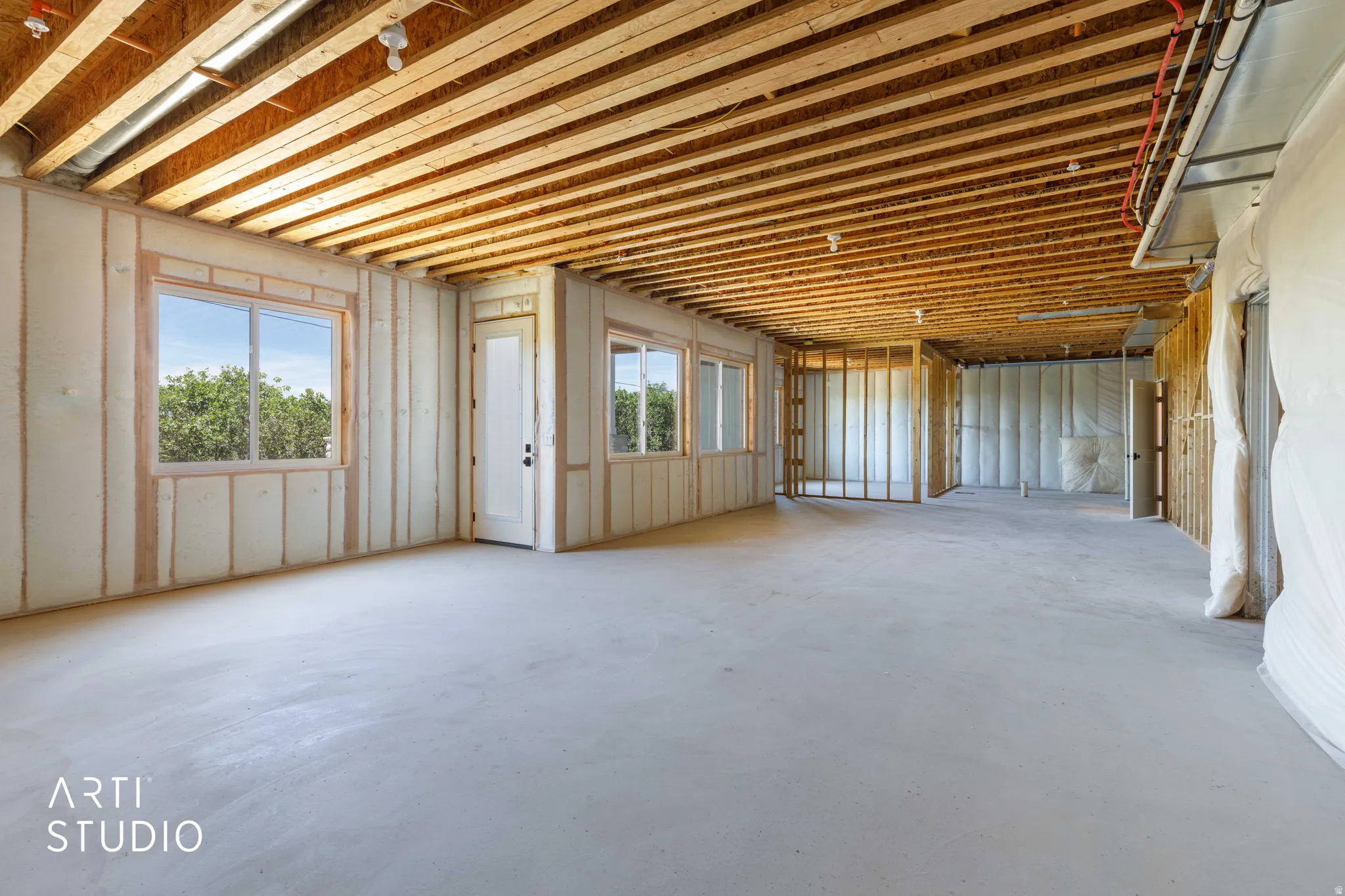 Unfinished lower level featuring exposed ceiling joists, framed walls, and multiple windows