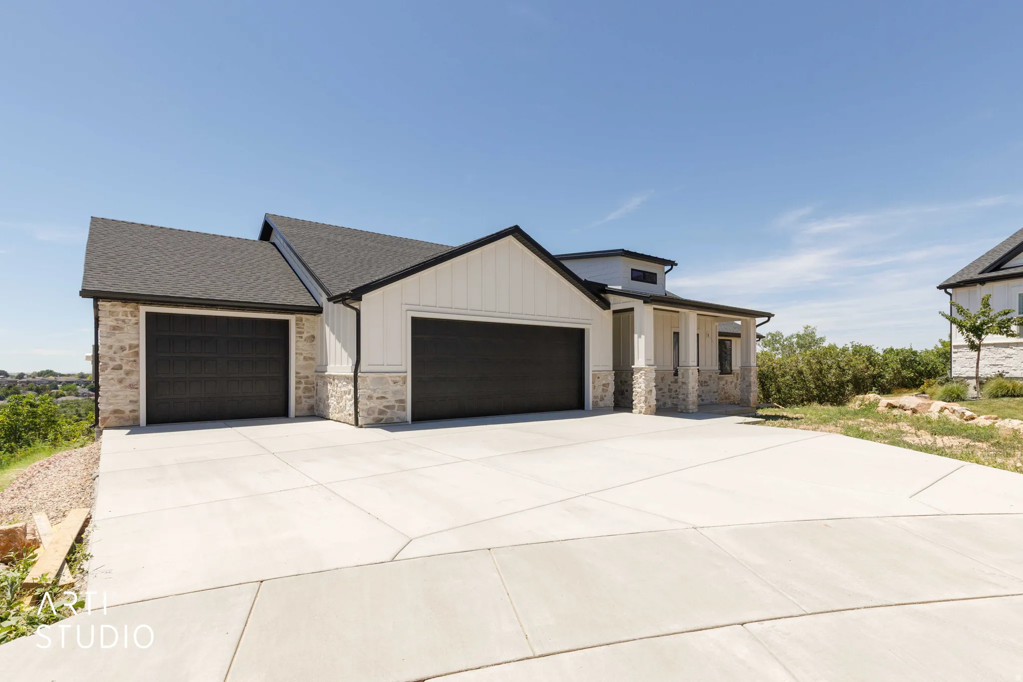 Contemporary home featuring a dual-tone exterior with white vertical siding and stone accents