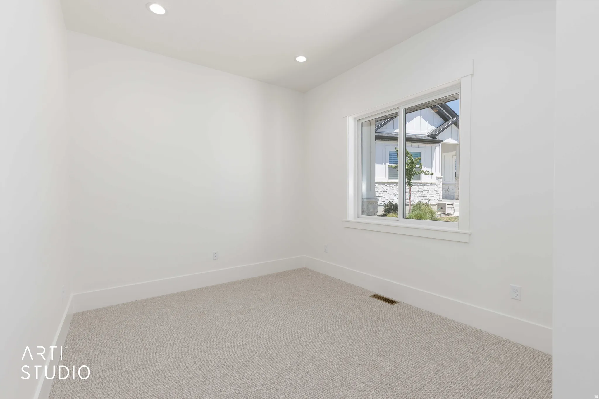 Bright room featuring recessed lighting, a large window with white trim, and light-colored carpeting