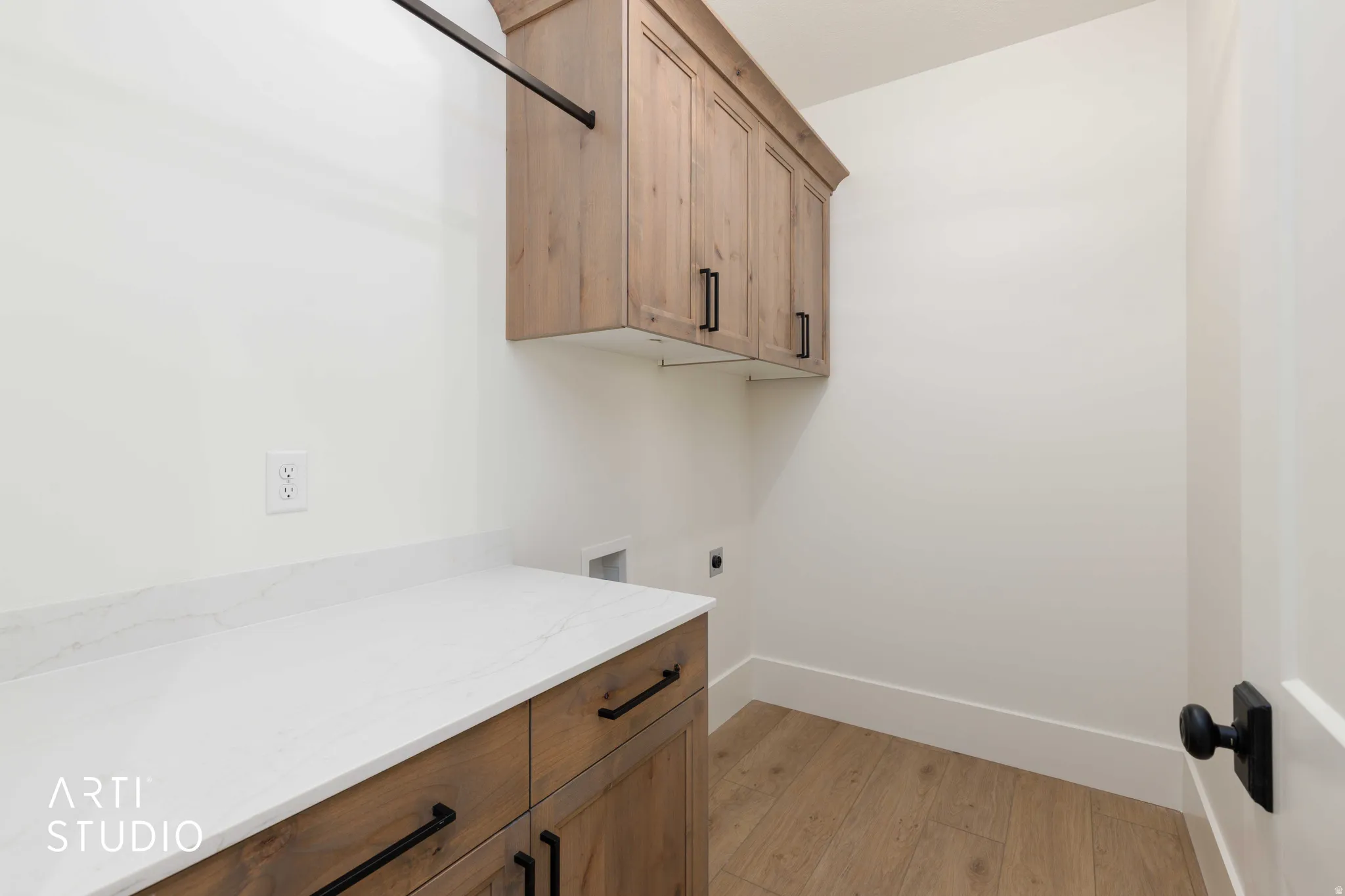 Laundry area featuring wood-finish flooring, white walls, and a quartz countertop
