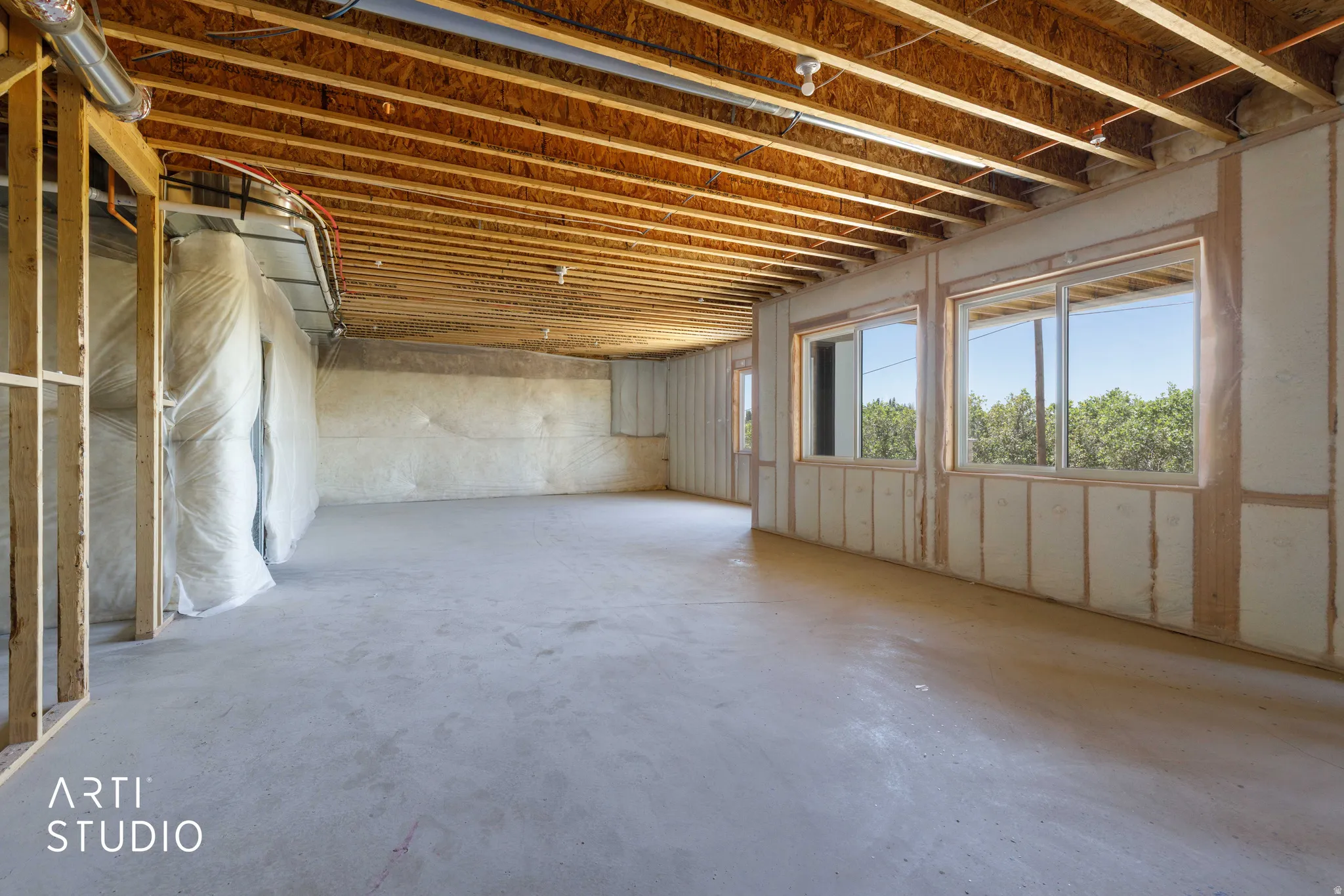 Unfinished basement with exposed ceiling joists and concrete flooring