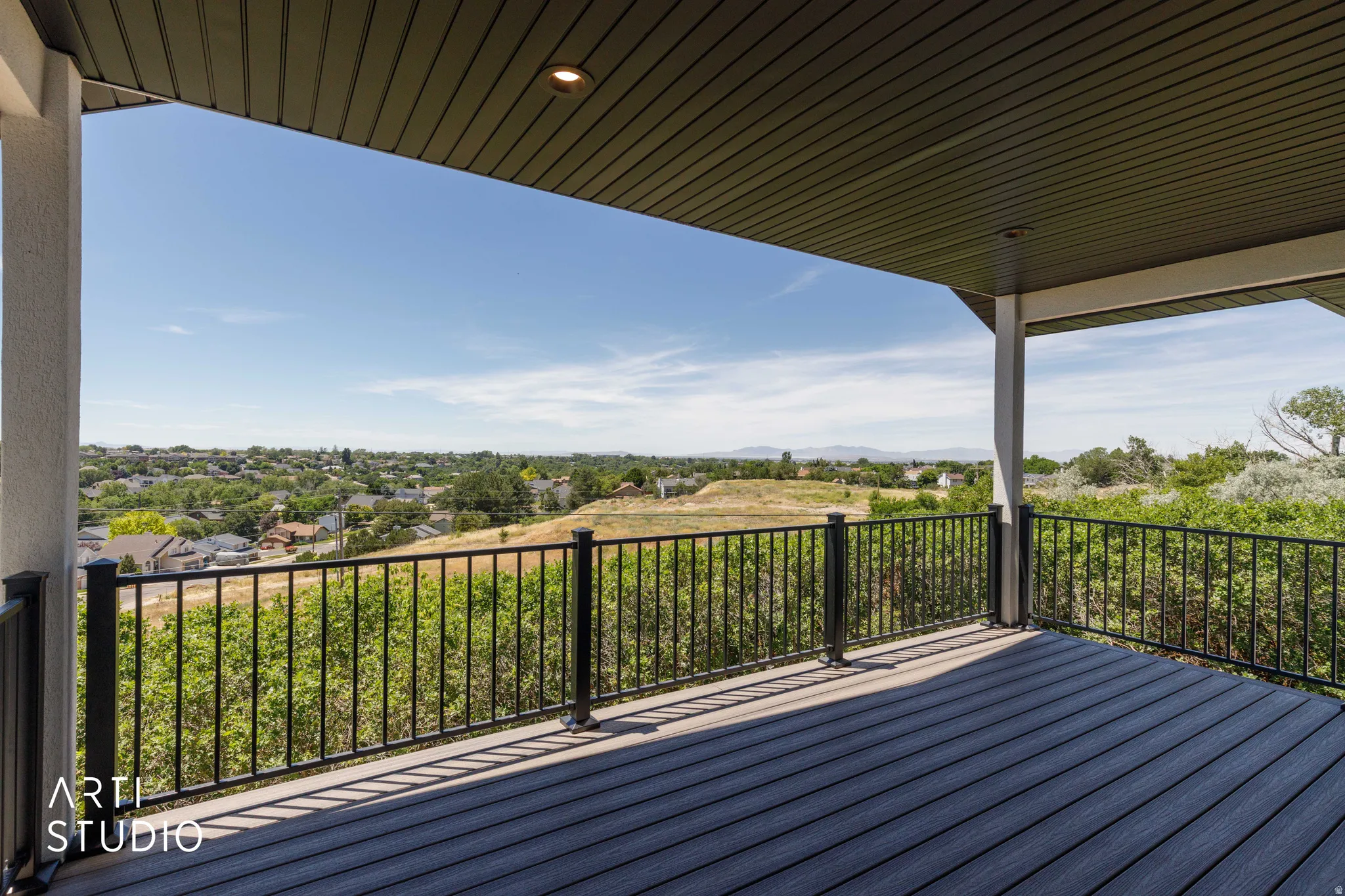 Covered outdoor deck with dark composite decking and black metal railings