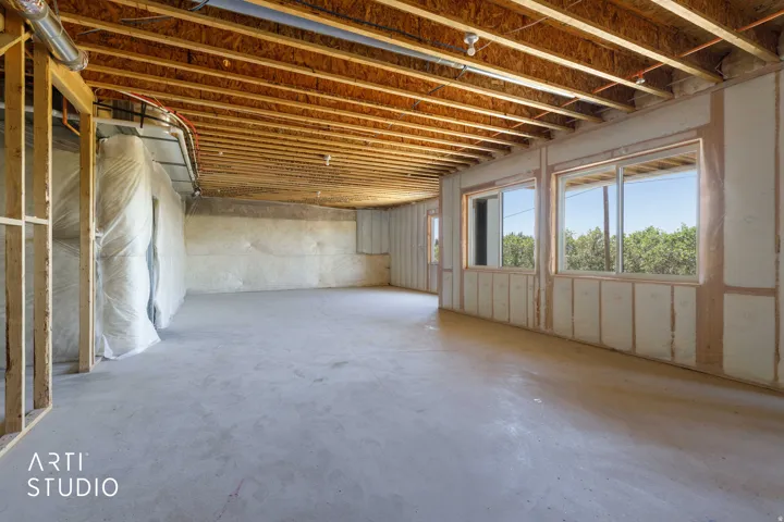 Unfinished basement with exposed ceiling joists and concrete flooring