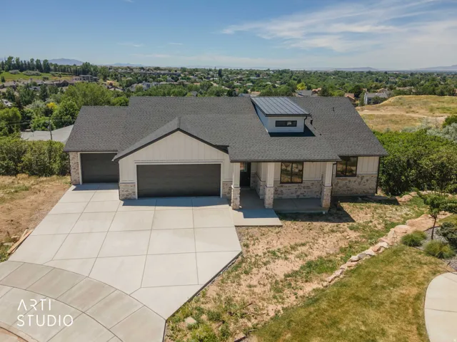 Contemporary residence featuring a gray shingled roof, white siding, and stone accents