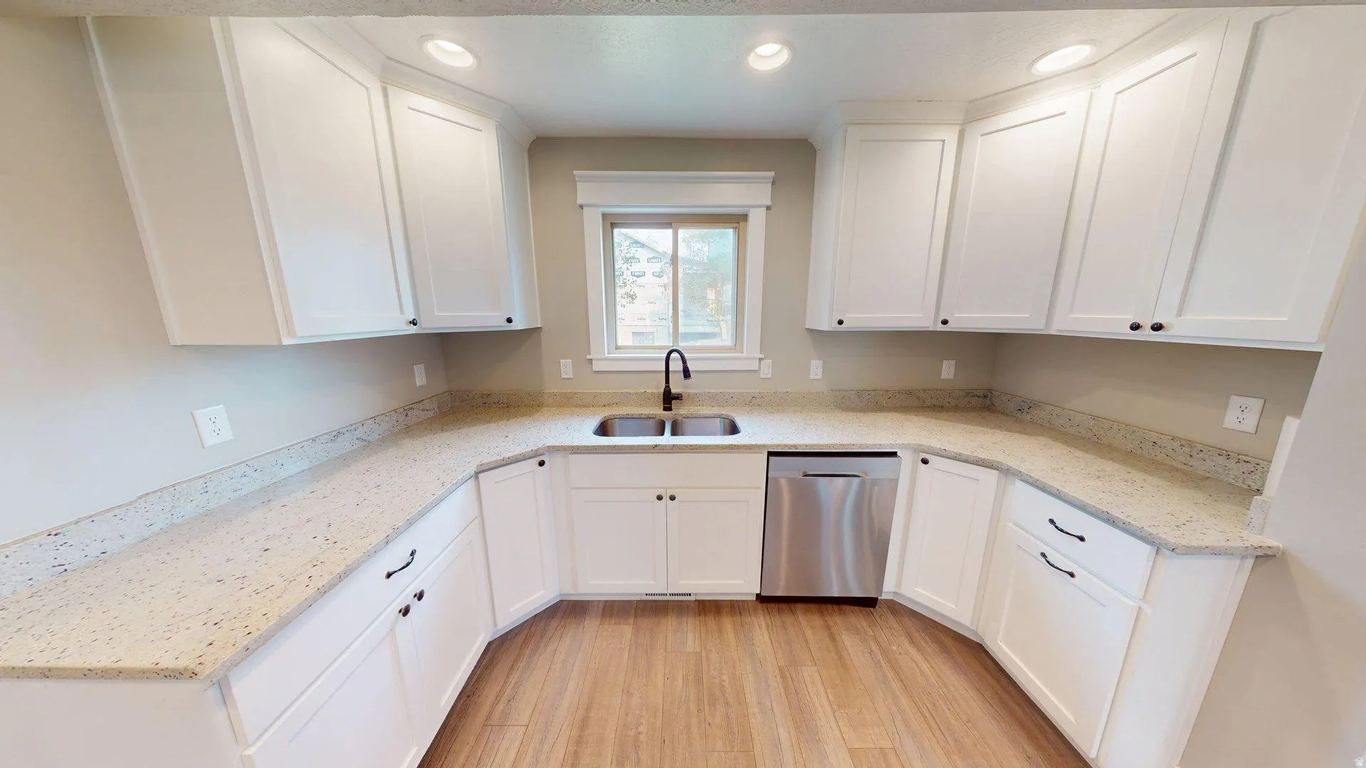 Kitchen featuring white cabinetry, stone-finish countertops, stainless steel dishwasher, wood-finish flooring, and a window above the sink