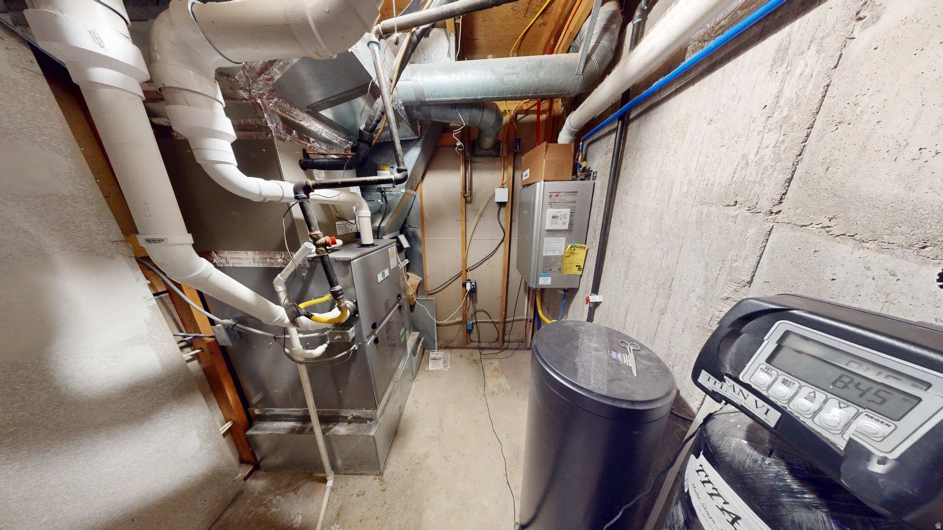 Utility area featuring a water softener system, furnace, and tankless water heater