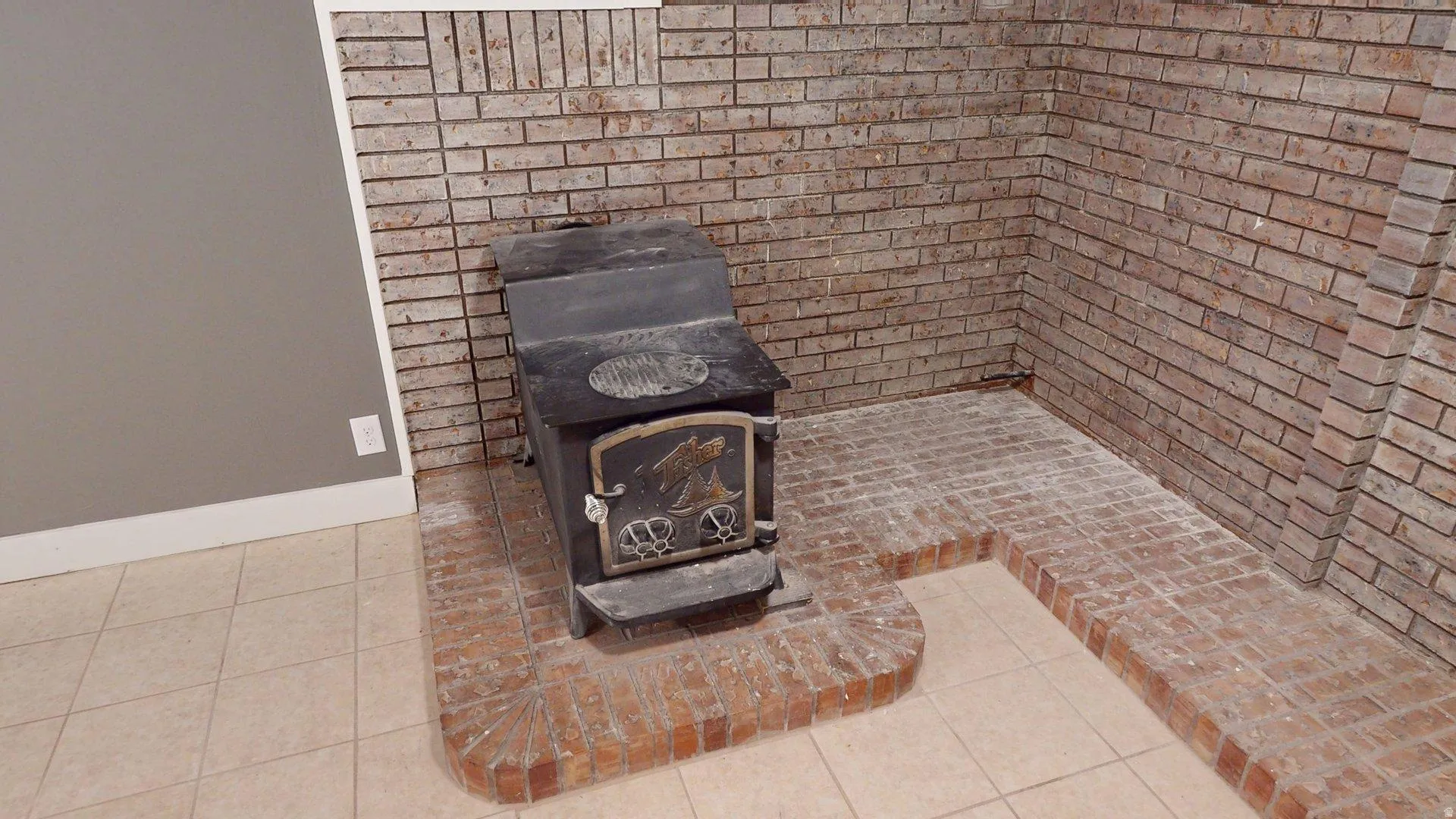 Brick-clad wall featuring a cast iron wood-burning stove on a raised brick hearth