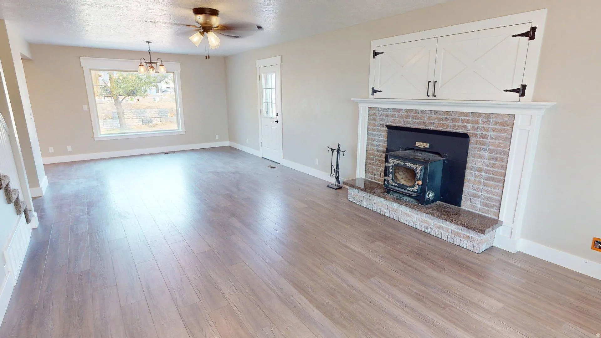 Spacious living area featuring wood-finish flooring and a fireplace with a wood-burning stove insert