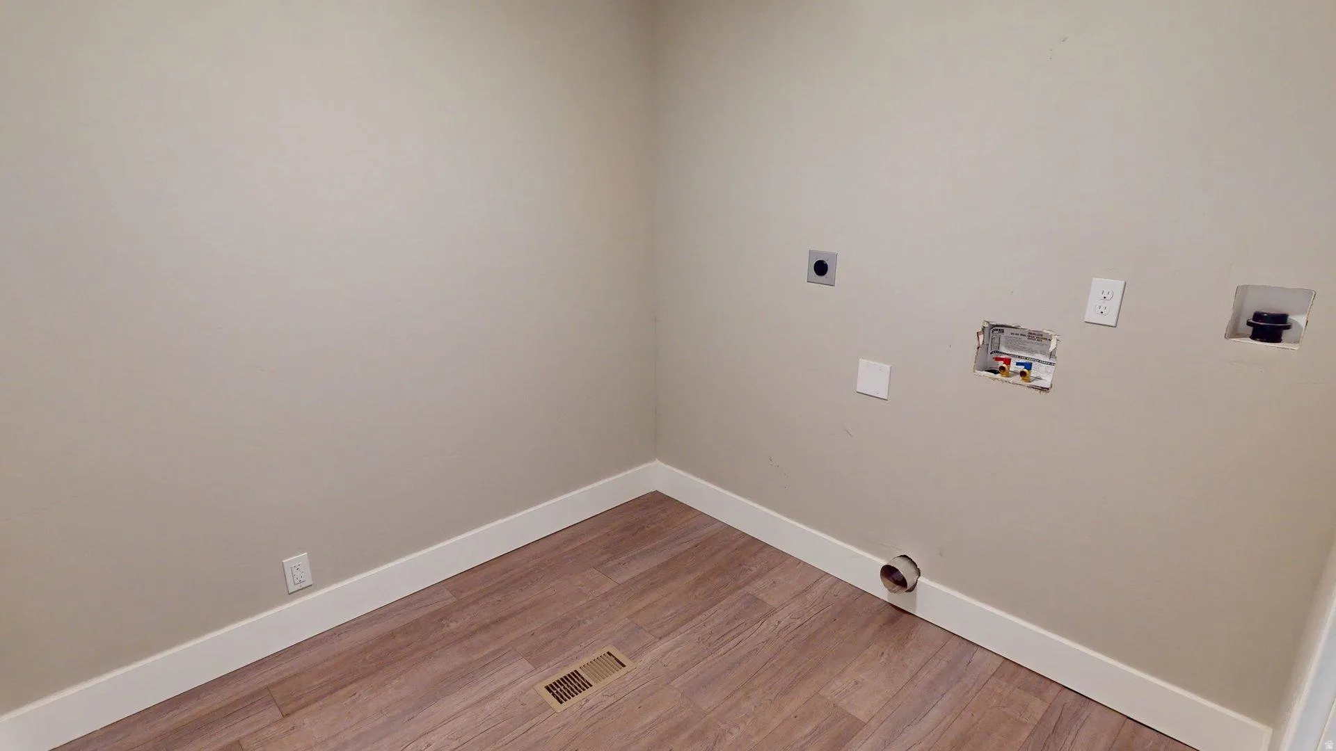 Utility space featuring wood-finish flooring, light-toned walls, and white baseboards