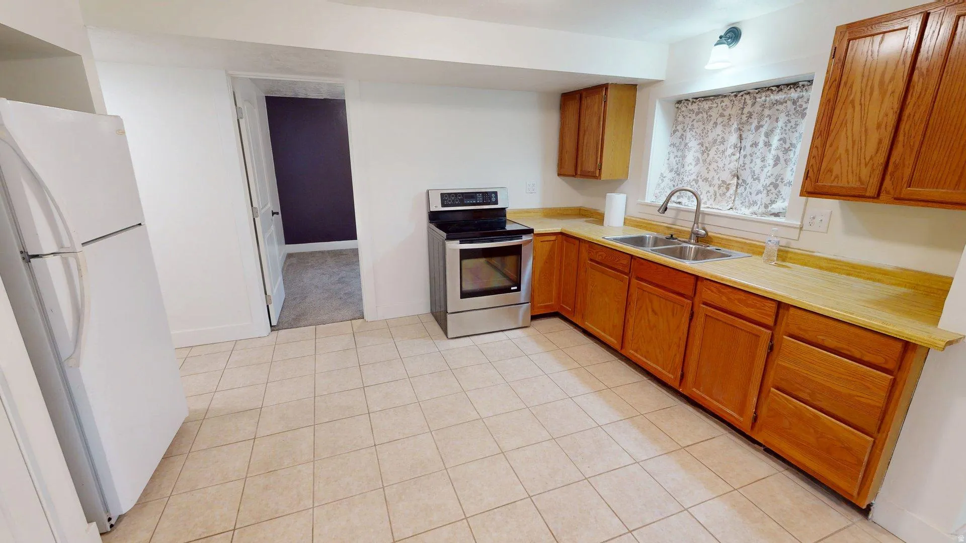 Kitchen featuring wood-finish cabinetry, a stainless steel range, and a double basin sink
