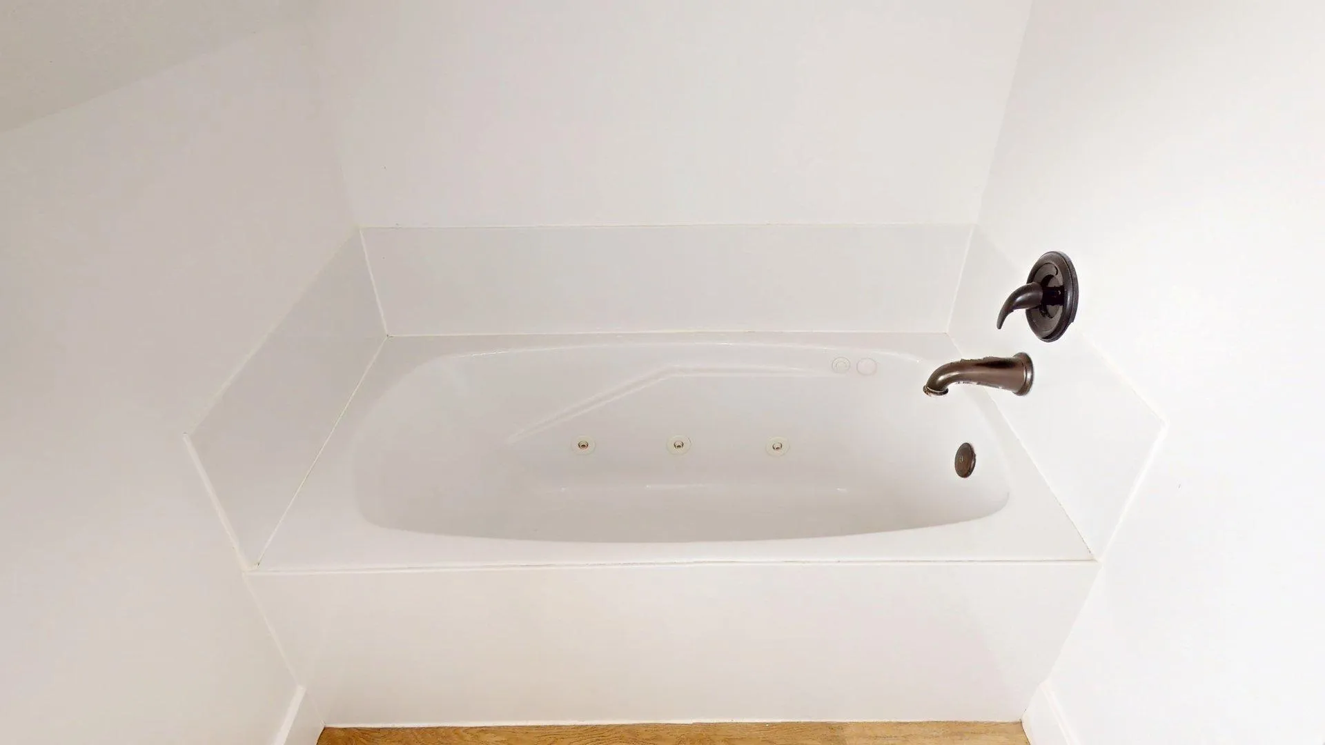 Built-in jetted tub featuring white surround and oil-rubbed bronze fixtures