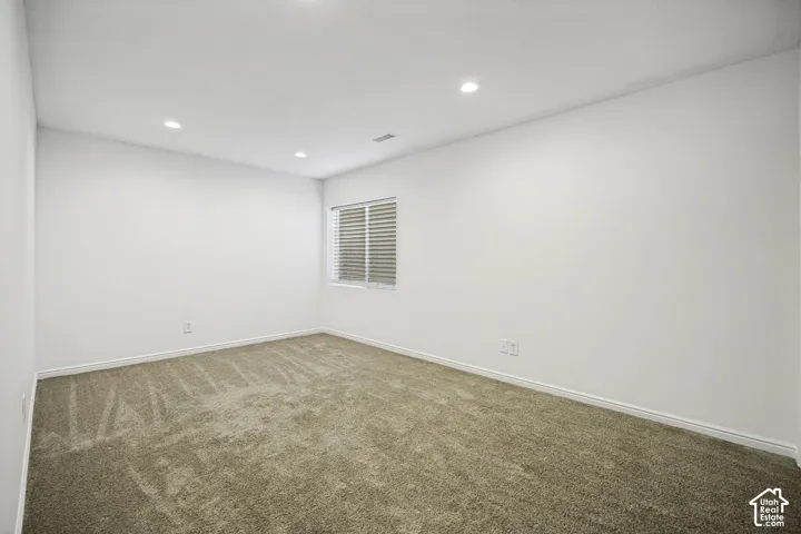 Carpeted room with recessed lighting and a window featuring horizontal blinds