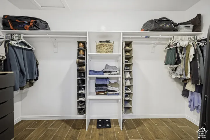 Customizable closet system featuring white shelving, hanging rods, and wood-finish flooring