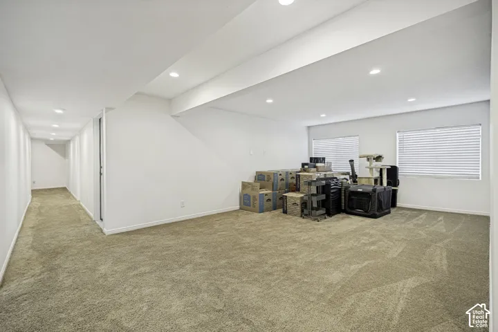 Expansive finished basement featuring recessed lighting, neutral carpeting, and two windows with blinds
