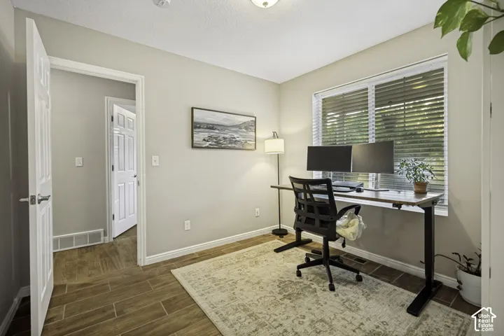 Room featuring wood-finish flooring, a double window with blinds, and light-toned walls