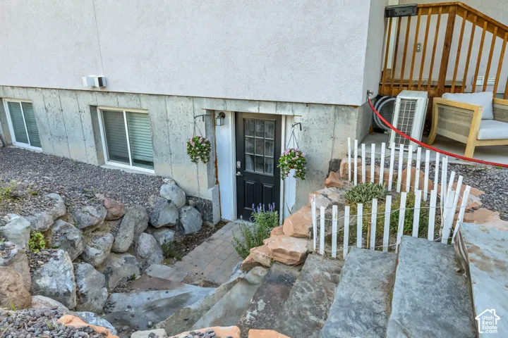 Lower-level entry with a dark panel door, bordered by decorative stonework and a stone slab pathway