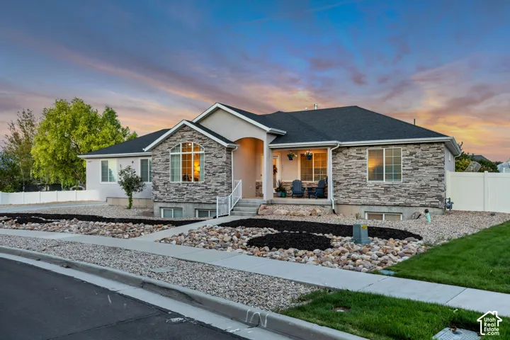 Exterior facade featuring stone veneer accents, stucco siding, and a dark shingle roof