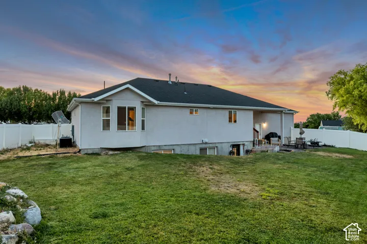 Expansive rear yard featuring a large patio area, walk-out basement access, and a durable privacy fence