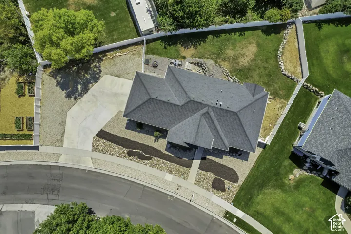 Gable roofline residence with an attached concrete driveway, gravel landscaping, and a manicured lawn