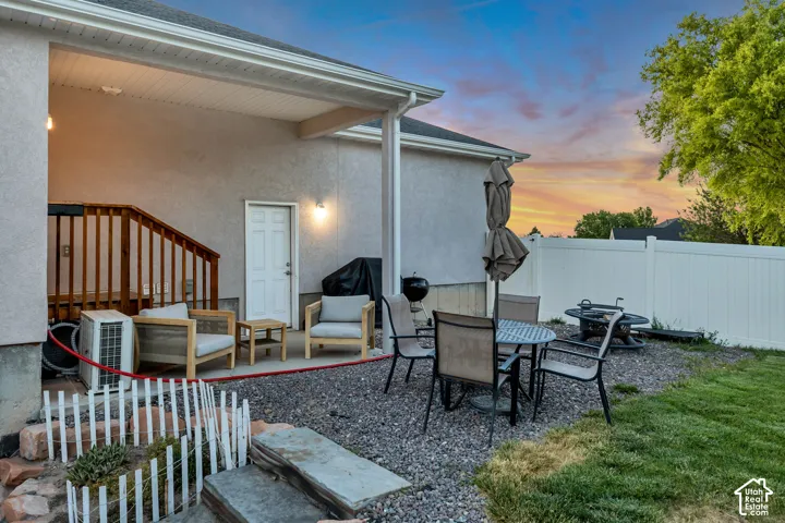 Covered patio featuring an exterior entry door, wood railing, and outdoor lighting